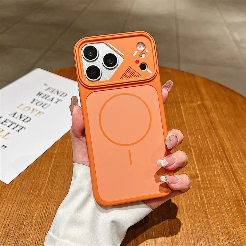 An orange magnetic phone case with a built-in stand, held by a hand over a wooden table. The case features a large circular MagSafe-compatible magnetic ring on the back, a raised camera bumper, and a small speaker grille.